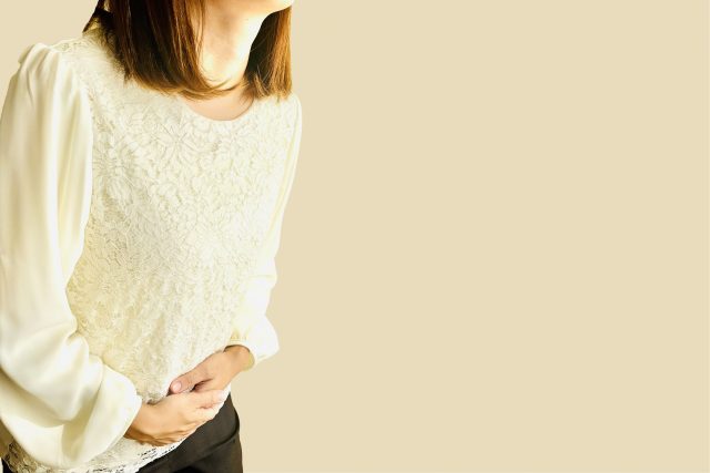 腹部をおさえる女性