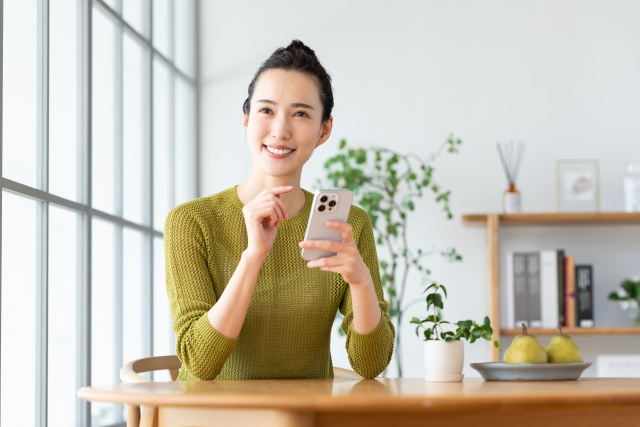 スマホを手にもって微笑む女性