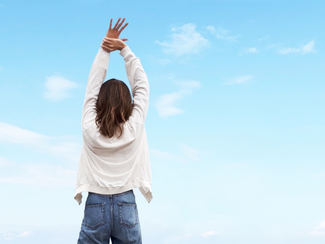 青空の下で背伸びする女性