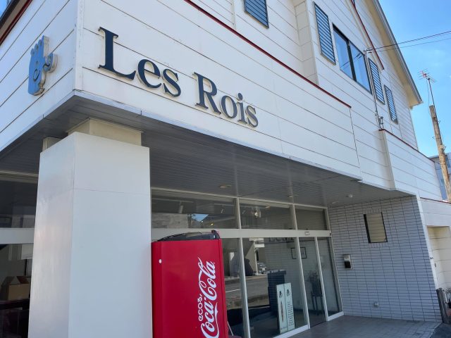 白い外壁に描かれた店名とコカ・コーラの自動販売機