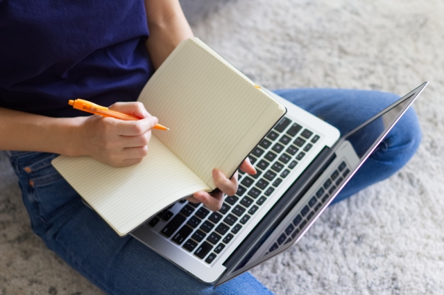 パソコンとノートを広げる女性