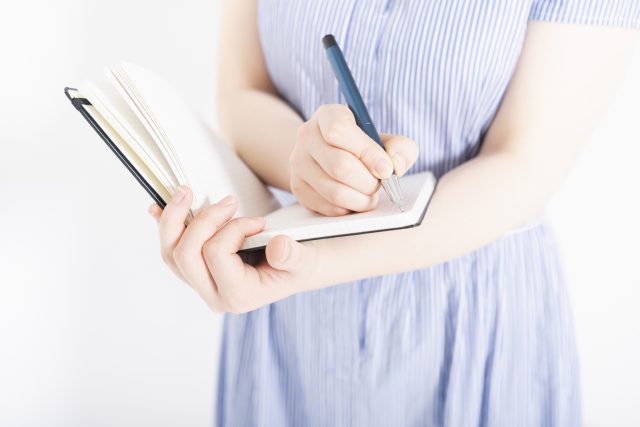 手帳にペンを走らせる女性