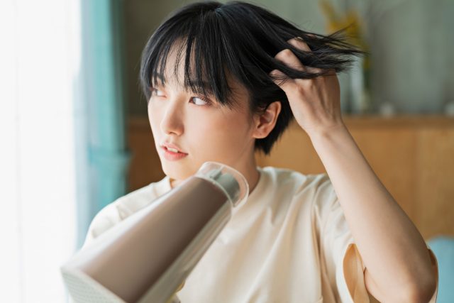 髪にドライヤーをかける朝の女性